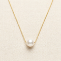 Gold freshwater pearl pendant necklace on cream background