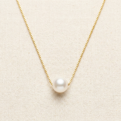 Gold freshwater pearl pendant necklace on cream background