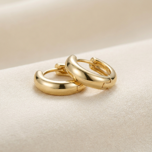 Gold huggie hoop earrings on cream background