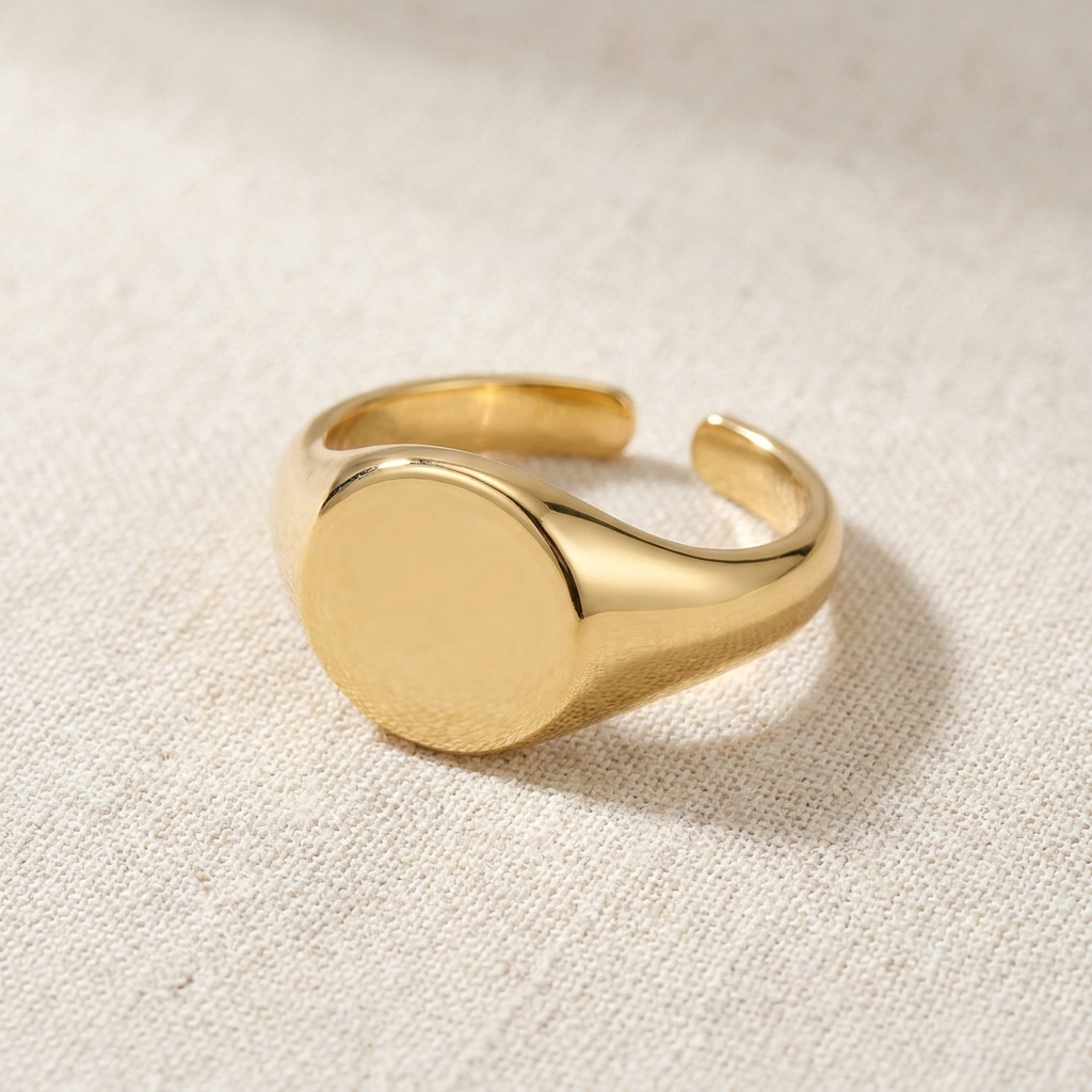 Gold adjustable signet ring on cream background